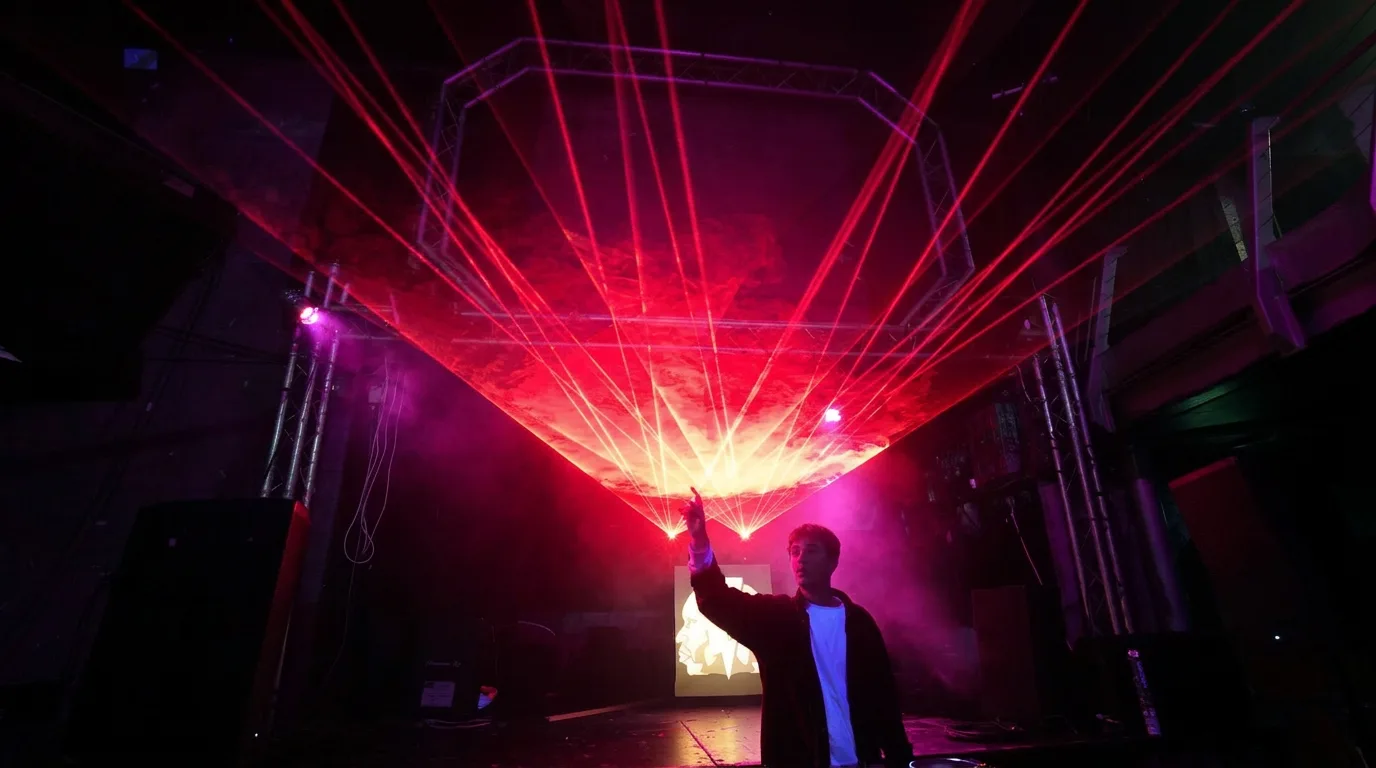 Laserist aiming a Nova RGB beam across a club venue